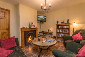 uma sala de estar com uma mesa e uma lareira em Mount Brandon Cottages Graiguenamanagh em Graiguenamanagh