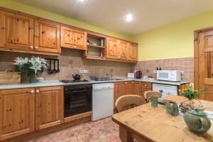 cocina con armarios de madera y mesa de madera en Mount Brandon Cottages Graiguenamanagh en Graiguenamanagh