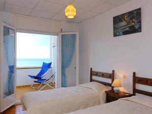 リャンサにあるApartment Puerto De La Selva-1 by Interhomeのベッドルーム1室(ベッド2台、青い椅子付)