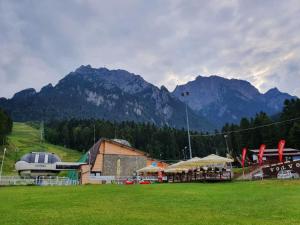 a building in a field with mountains in the background at Apartament Eric, Busteni in Buşteni