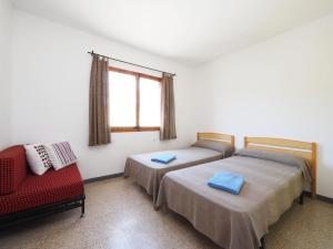 2 camas en una habitación con una silla roja y una ventana en Apartment AGUS by Interhome, en Port de la Selva