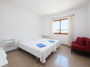 1 dormitorio con 2 camas y silla roja en Apartment AGUS by Interhome, en Port de la Selva