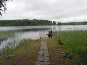 a person sitting on a bench next to a lake at Holiday Home Helmiranta by Interhome in Saarijärvi