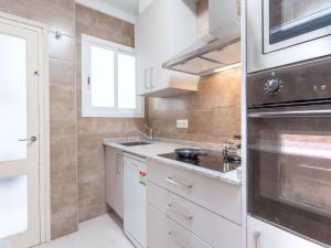 Una cocina con gabinetes blancos y un horno de estufa. en Apartment Ronda by Interhome, en L'Escala