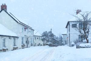 una calle cubierta de nieve en una ciudad con casas en The Rest and Be Thankful Inn en Minehead