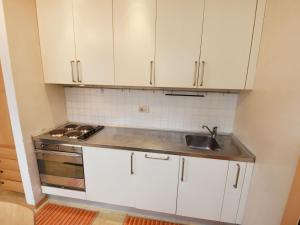een keuken met witte kasten en een wastafel bij Apartment Enrosadira-4 by Interhome in Alba di Canazei