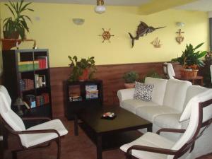 a living room with a white couch and two chairs at Hotel Brisamar in Bañugues
