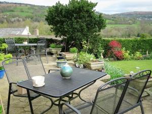a table and chairs with a vase on top of it at Cae y Rhedyn Annexe in Crickhowell