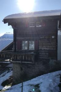 a log cabin in the snow with the sun in the background at Apartment Stubulti by Interhome in Mörel