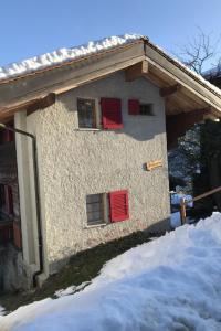 a house with red shuttered windows in the snow at Apartment Stubulti by Interhome in Mörel