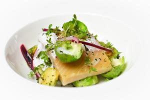 a white plate of food with fish and a salad at Tomelilla Golf Hotell in Tomelilla