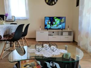 un soggiorno con tavolo in vetro e TV di Apartment Vera Nin a Nin