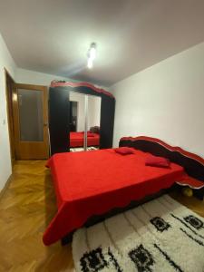 een slaapkamer met een rood bed en een spiegel bij Friend's House in Piteşti