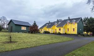 a yellow house with a black roof and a driveway at Mount Brandon Cottages Graiguenamanagh in Graiguenamanagh