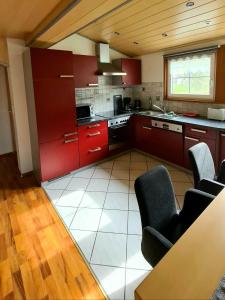 een keuken met rode kasten en een tafel en stoelen bij Ferienwohnungen Claudia in Altossiach