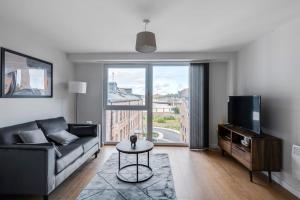 a living room with a couch and a tv at Spacious 1 Bedroom Apartment in a Converted Mill in Leeds