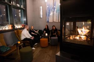 a group of people sitting in a room with a fireplace at Svalbard Hotell | Polfareren in Longyearbyen