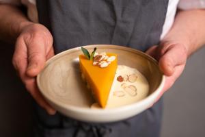 a person holding a plate with a piece of food at Svalbard Hotell | Polfareren in Longyearbyen