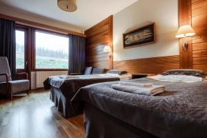 a hotel room with two beds and a window at Lapland Hotels Saaga in Ylläsjärvi