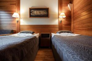 two beds in a room with wooden walls at Lapland Hotels Saaga in Ylläsjärvi
