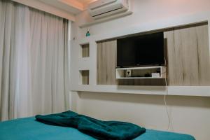 1 dormitorio con 1 cama y TV en la pared en Qavi - Flat Beira Mar Cotovelo #InMare224, en Parnamirim