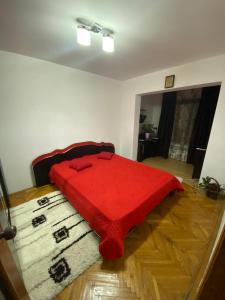 un letto rosso posto sopra un pavimento in legno di Friend's House a Piteşti