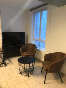 歐德梅爾橋的住宿－la licorne { T2 tous confort} centre ville，客厅配有两把椅子、一张桌子和电视