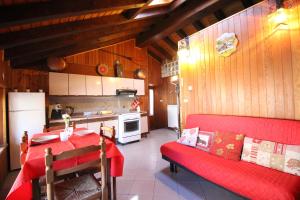 cocina con mesa roja y sofá rojo en Appartamento Il Camoscio - Affitti Brevi Italia en Brusson