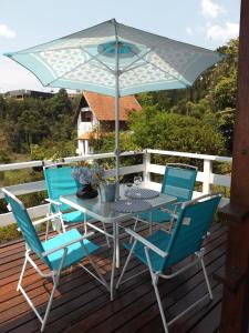 une table et des chaises sur une terrasse avec un parasol dans l'établissement Chalés Alto do Capivari, à Campos do Jordão