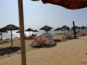 a row of tents on a beach with the ocean at Cartaia Apartamento Leste in Quarteira