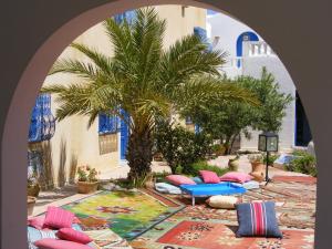 an archway with pillows and a palm tree in a courtyard at Dar Amphora Menzel in Midoun