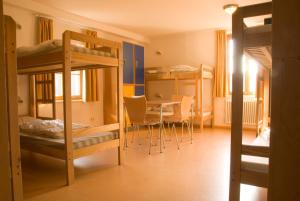 Habitación con literas, mesa y sillas. en Youth Hostel Vianden en Vianden