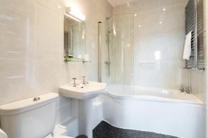 a white bathroom with a sink and a toilet and a tub at Manor House Hotel Holy Island in Berwick-Upon-Tweed