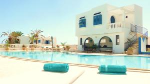 a swimming pool with two blue pillows in front of a house at Dar Amphora Menzel in Midoun