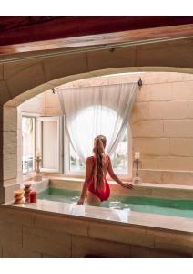 Lulu Boutique Hotel في Żebbuġ: امرأة جالسة في حوض الاستحمام في حمام السباحة