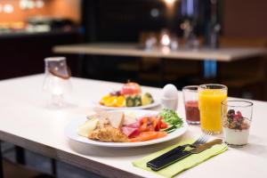 einem Tisch mit zwei Teller Essen und einem Glas Orangensaft in der Unterkunft Svalbard Hotell | The Vault in Longyearbyen