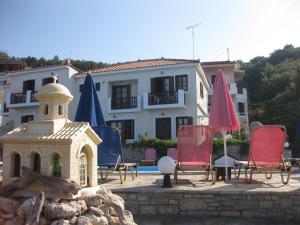 a group of chairs and umbrellas in front of a building at Violetta Seaside Studios&Apartments in Karlovasi