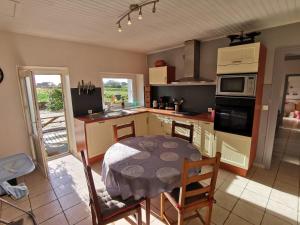 Santec的住宿－Gîte bord de mer，一间带桌子的厨房和一间带桌椅的厨房