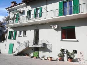 Edificio blanco con puertas verdes y balcón en Gorizia vacanze, en Gorizia