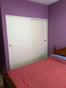 a bedroom with a bed and a purple wall at Atlantis Park in Mar de Ajó