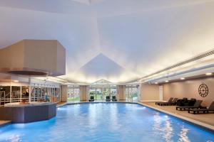 a large swimming pool in a hotel with chairs and tables at Coldra Court Hotel by Celtic Manor in Newport