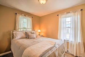 a bedroom with a bed with white curtains and a window at Cottage with Yard, Walk to Historic Attractions! in Sainte Genevieve