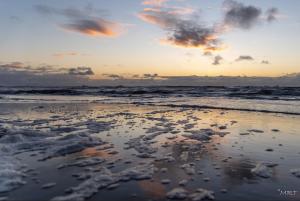 a view of the beach at sunset with the ocean at Hotel Steeds aan Zee in Katwijk