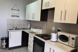 a kitchen with white cabinets and a microwave oven at Centurion Fully furnished lock up&go 1 bedroom apartment in Centurion