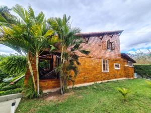 a brick house with a palm tree in front of it at Chalé aconchegante na Serra Pernambucana - Em condomínio - Gravatá in Gravatá