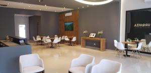 Urquiza Suites Salta في سالتا: غرفة انتظار وكراسي بيضاء وطاولات وشاشة
