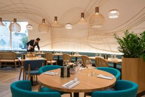 a man standing in a restaurant with tables and chairs at Novotel Nice Arenas Aeroport in Nice