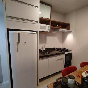 a kitchen with a refrigerator and a microwave at Loft encantador C - 8 km de Floripa in São José