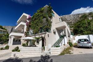 a white building with a car parked in front of it at Apartmani Antonela in Drasnice