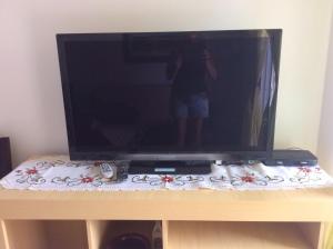 a person standing in front of a television on a table at EXCELENTE APTO NA QUADRA DA PRAIA in Bombas